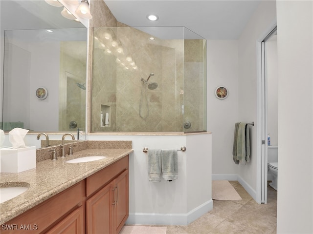 full bathroom featuring double vanity, toilet, a sink, a walk in shower, and baseboards