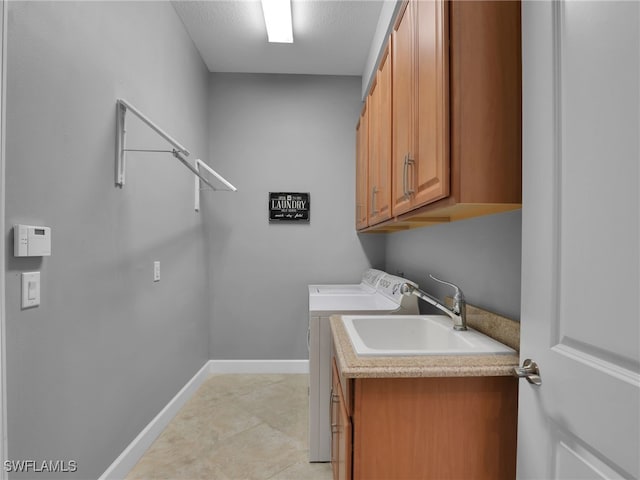 washroom featuring separate washer and dryer, a sink, cabinet space, and baseboards