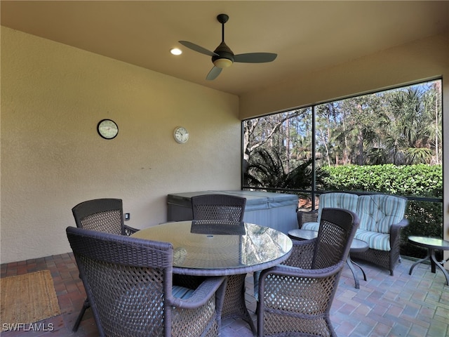 view of patio with ceiling fan, outdoor dining area, and a hot tub