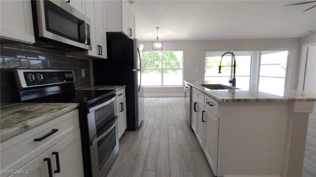 kitchen with stainless steel appliances, sink, a center island with sink, and white cabinets