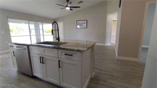 kitchen featuring sink, dishwasher, light stone countertops, white cabinets, and a center island with sink