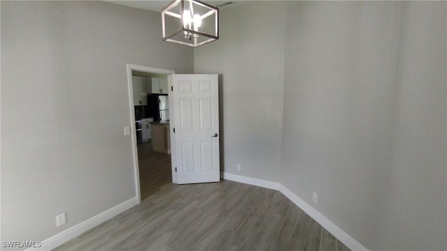 empty room with an inviting chandelier and light wood-type flooring