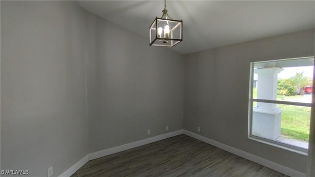 unfurnished room featuring dark hardwood / wood-style floors and a notable chandelier