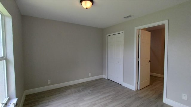 unfurnished bedroom featuring light hardwood / wood-style flooring and a closet