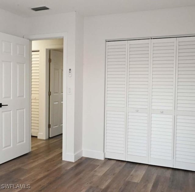 unfurnished bedroom featuring dark hardwood / wood-style flooring and a closet