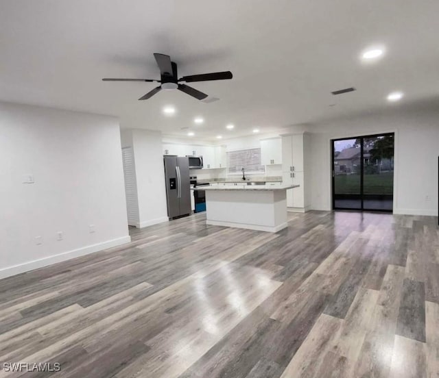 unfurnished living room with ceiling fan, sink, and light wood-type flooring