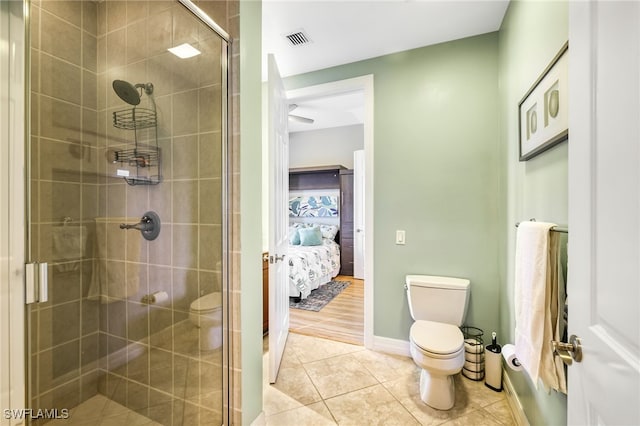 bathroom with tile patterned floors, toilet, and a shower with shower door