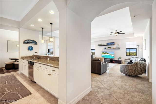 kitchen with sink, white cabinetry, dark stone countertops, decorative light fixtures, and stainless steel dishwasher