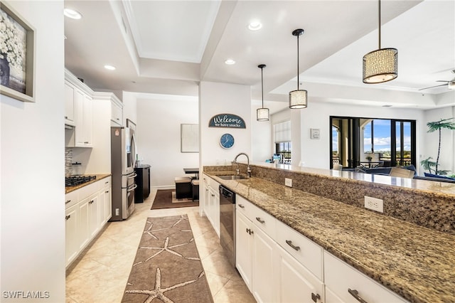 kitchen with appliances with stainless steel finishes, decorative light fixtures, white cabinetry, sink, and dark stone countertops