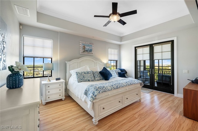 bedroom with crown molding, a tray ceiling, access to outside, and light hardwood / wood-style floors