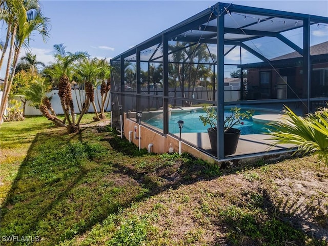 view of swimming pool featuring a yard and glass enclosure