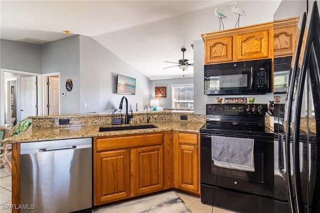 kitchen featuring sink, light stone counters, vaulted ceiling, kitchen peninsula, and black appliances