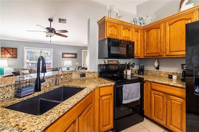 kitchen with sink, crown molding, light tile patterned floors, black appliances, and light stone countertops