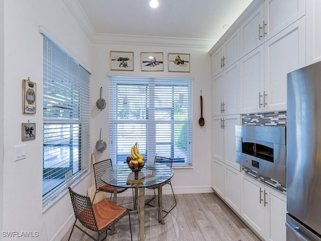 dining space with crown molding and light hardwood / wood-style flooring