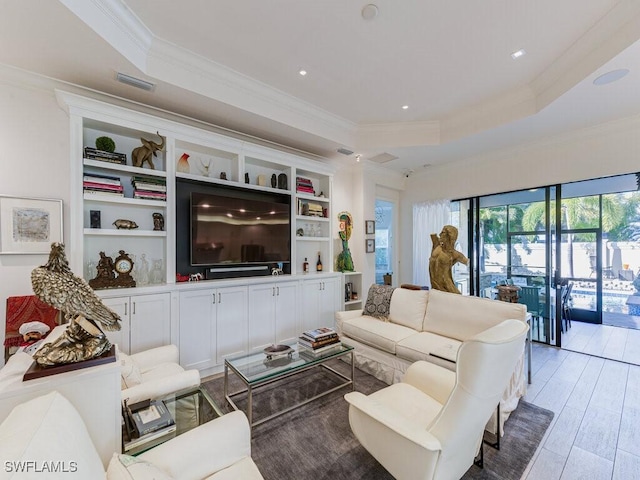 living room featuring crown molding, a tray ceiling, wood-type flooring, and built in shelves