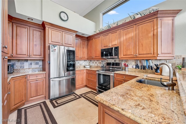 kitchen featuring stainless steel appliances, light stone countertops, and sink