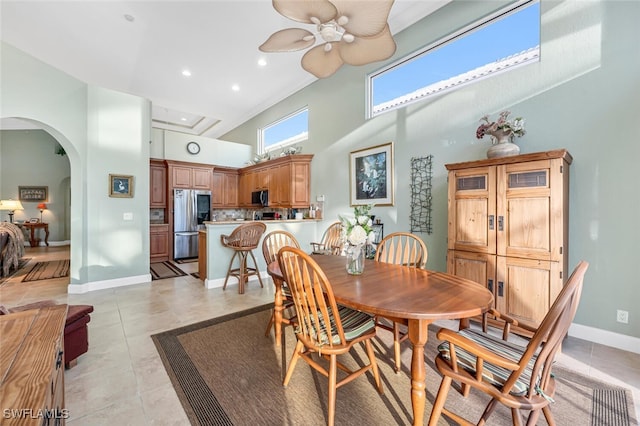 dining area featuring light tile patterned floors, ceiling fan, and a high ceiling