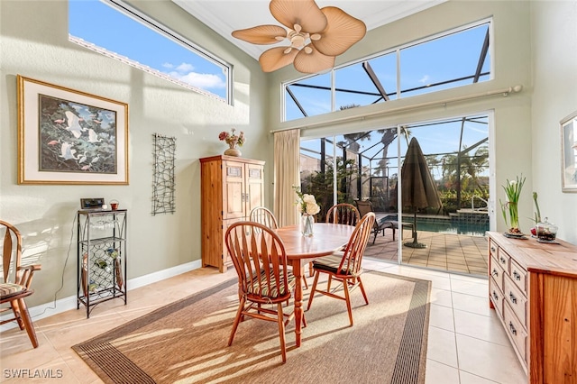 dining area featuring a towering ceiling, ornamental molding, a sunroom, light tile patterned flooring, and baseboards