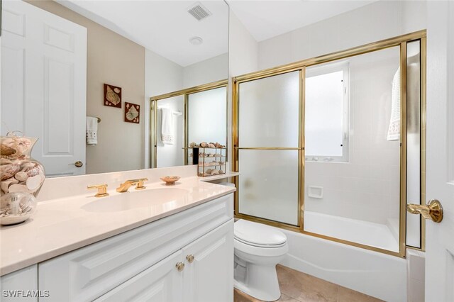 bathroom with shower / bath combination with glass door, visible vents, toilet, vanity, and tile patterned flooring