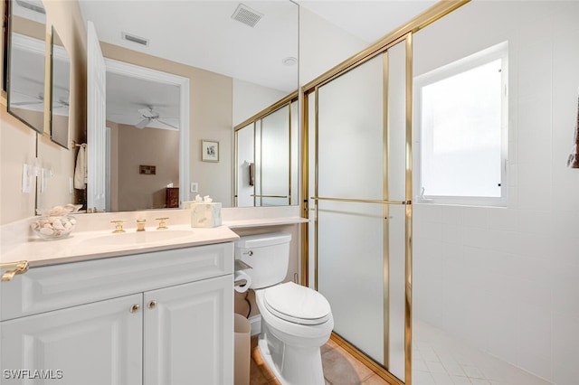 bathroom with an enclosed shower, vanity, toilet, and ceiling fan