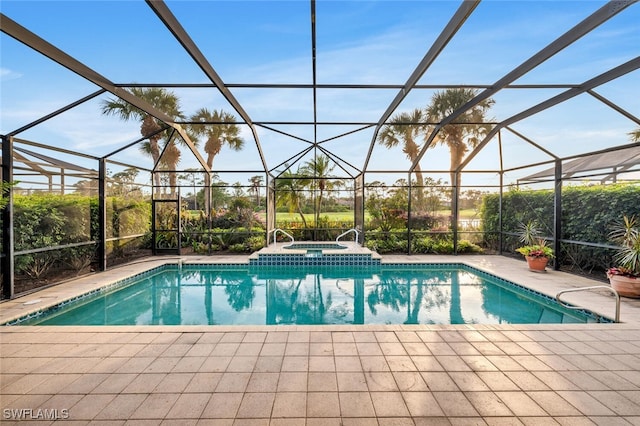 view of pool featuring glass enclosure, a pool with connected hot tub, and a patio