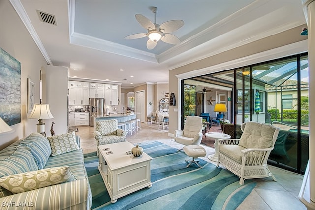 tiled living room featuring ornamental molding, ceiling fan, and a tray ceiling