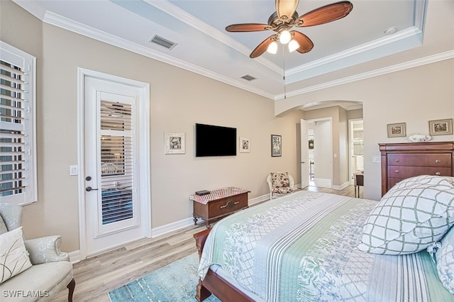 bedroom featuring ornamental molding, light hardwood / wood-style flooring, and a tray ceiling