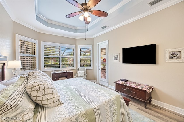 bedroom featuring access to exterior, a tray ceiling, light hardwood / wood-style flooring, and ornamental molding