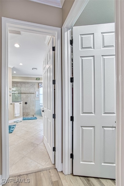 hallway featuring crown molding and light hardwood / wood-style flooring