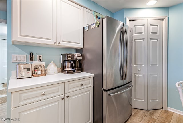 kitchen featuring stainless steel fridge, light hardwood / wood-style floors, and white cabinets