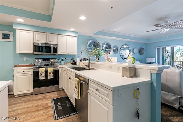 kitchen with sink, white cabinetry, light hardwood / wood-style flooring, appliances with stainless steel finishes, and kitchen peninsula