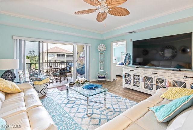 living room with wood-type flooring, crown molding, and ceiling fan