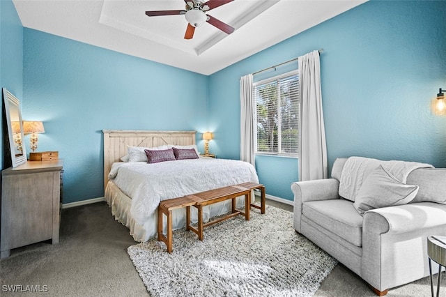 bedroom featuring ceiling fan, a tray ceiling, and carpet