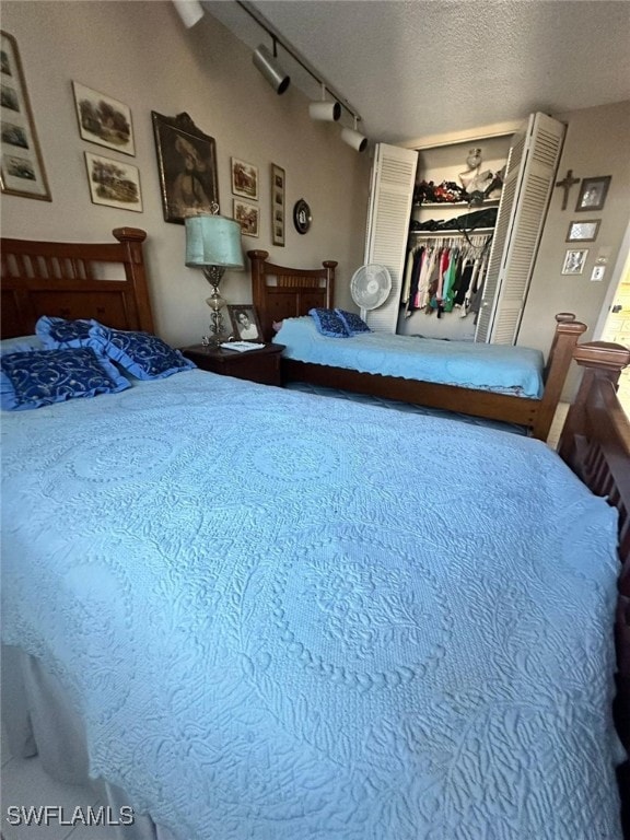 bedroom featuring a closet, track lighting, and a textured ceiling