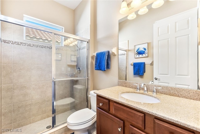 bathroom with a shower with door, vanity, and toilet