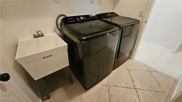 laundry area featuring light tile patterned flooring, separate washer and dryer, and sink