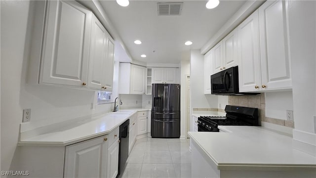 kitchen featuring sink, light tile patterned floors, white cabinetry, tasteful backsplash, and black appliances