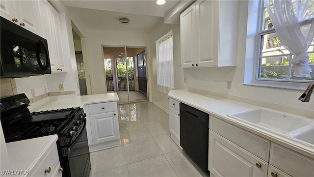 kitchen featuring sink, light tile patterned floors, a wealth of natural light, black appliances, and white cabinets