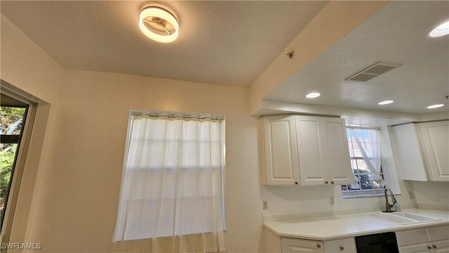 kitchen with white cabinetry, sink, and a textured ceiling