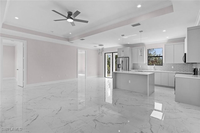 kitchen with stainless steel refrigerator with ice dispenser, a tray ceiling, hanging light fixtures, and a kitchen island