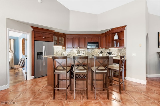 kitchen featuring tasteful backsplash, high vaulted ceiling, light tile patterned flooring, and appliances with stainless steel finishes