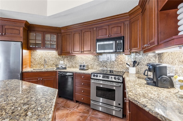 kitchen featuring sink, tasteful backsplash, light stone counters, appliances with stainless steel finishes, and tile patterned flooring