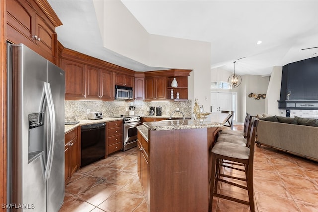 kitchen featuring hanging light fixtures, a kitchen breakfast bar, stainless steel appliances, light stone countertops, and decorative backsplash