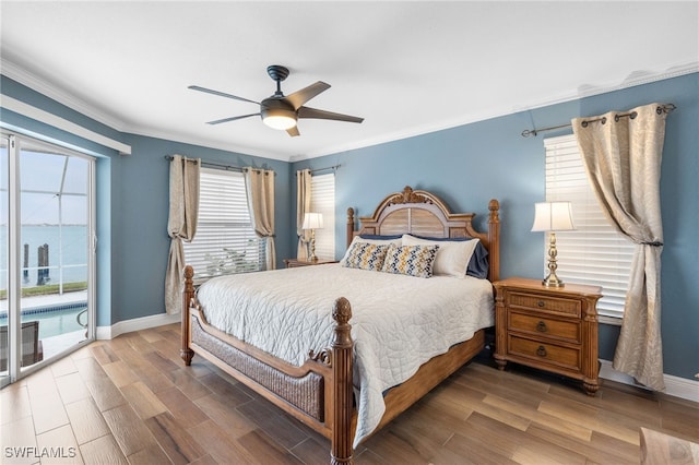 bedroom with hardwood / wood-style floors, access to outside, ornamental molding, and a water view