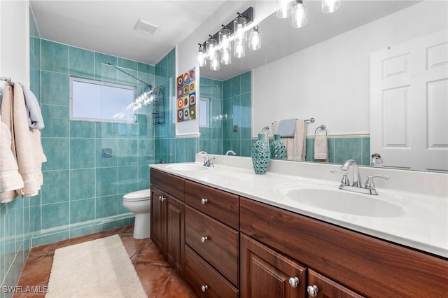 bathroom featuring tile patterned flooring, tile walls, vanity, a tile shower, and toilet