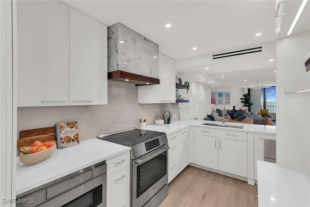 kitchen with white cabinetry, appliances with stainless steel finishes, light hardwood / wood-style floors, and sink