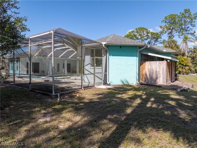 back of property with a yard, a patio area, and glass enclosure