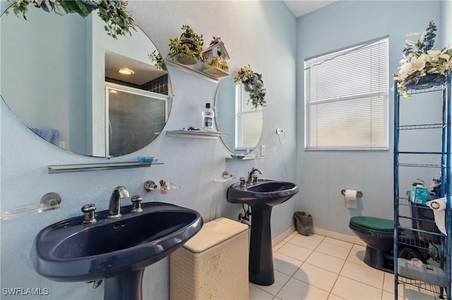 bathroom featuring toilet, sink, a shower with shower door, and tile patterned flooring