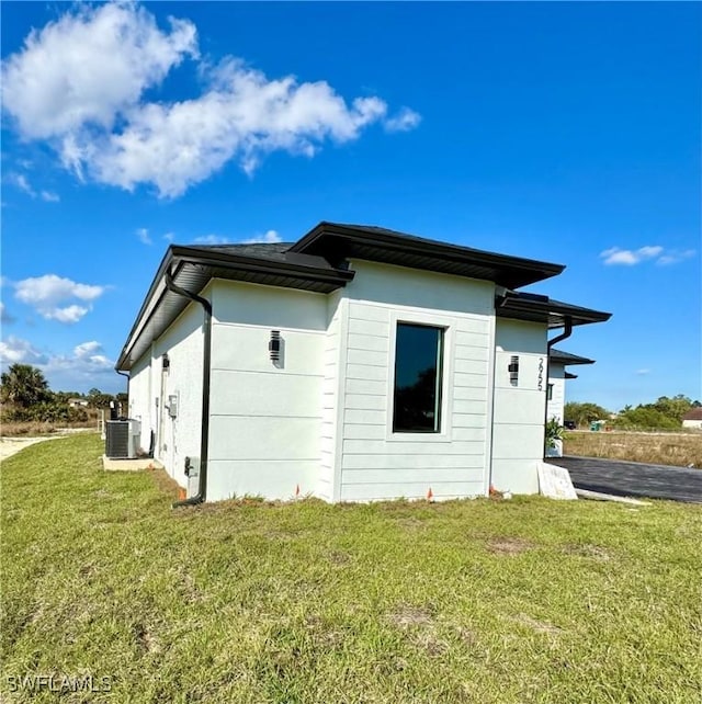 view of side of property with cooling unit and a yard