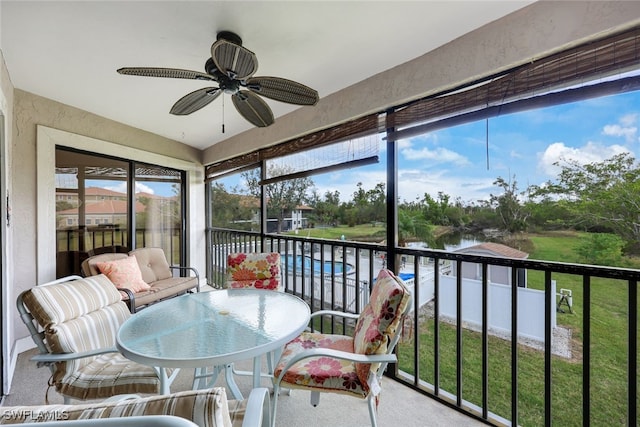 sunroom featuring a water view and ceiling fan